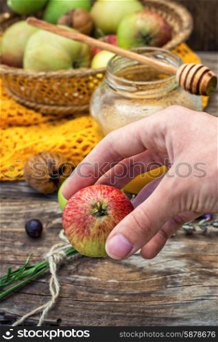 apple and honey. apple in hand on the background of the glass jar with fragrant honey and fruits