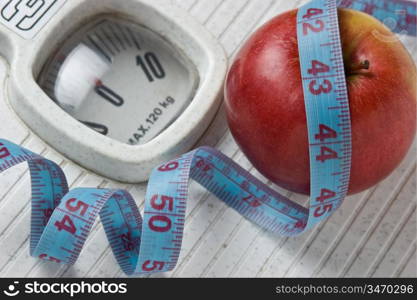 apple and measuring tape on the floor scales isolated on white