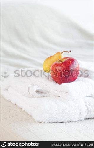 apple and pear on towels on the bed