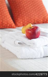 apple and pear on towels on the bed with two pillows