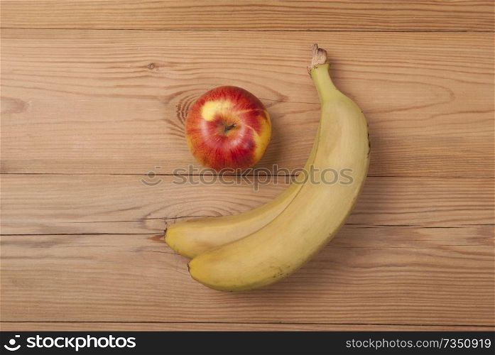 Apple and ripe bananas lie on a wooden background.. Apple and ripe bananas .
