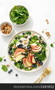 Apple and spinach fresh sweet fruit salad with blueberry, cheese cottage and walnuts, top view