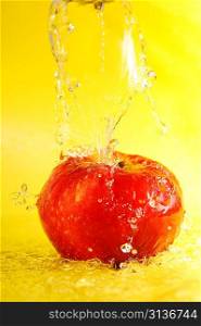 apple and water splashes on yellow close up
