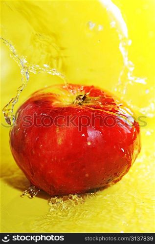 apple and water splashes on yellow close up