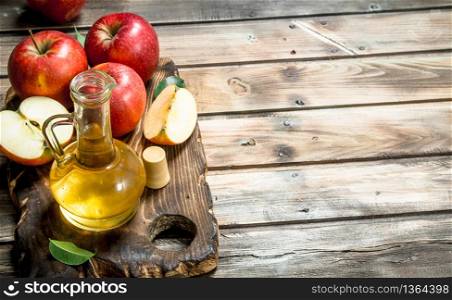Apple cider vinegar with fresh red apples on a cutting Board. On grey wooden background.. Apple cider vinegar with fresh red apples on a cutting Board.