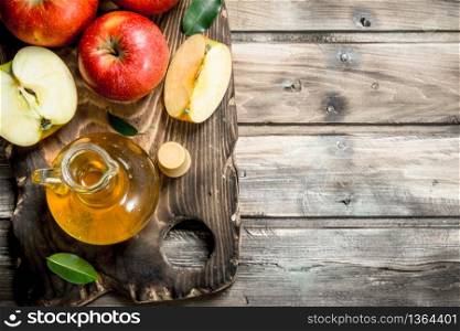 Apple cider vinegar with fresh red apples on a cutting Board. On grey wooden background.. Apple cider vinegar with fresh red apples on a cutting Board.
