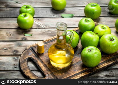 Apple cider vinegar with green apples on an old Board. On grey wooden backgroun. Apple cider vinegar with green apples on an old Board.