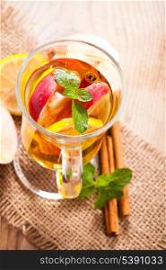 Apple, cinnamon and citrus beverage with twig of mint