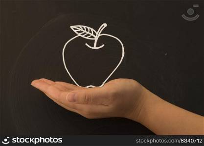 apple in hand on blackboard. holding a apple in hand on blackboard