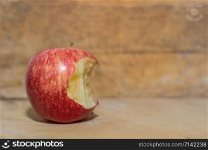 Apple is bitten on a wooden floor.