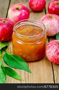 Apple jam in a glass jar, fresh red apples and leaves on wooden board
