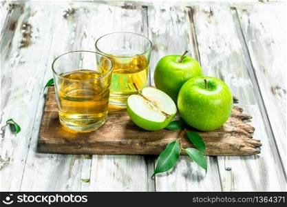 Apple juice in a glass Cup on a wooden Board. On a white wooden background.. Apple juice in a glass Cup on a wooden Board.
