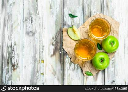 Apple juice in a glass Cup on a wooden Board. On a white wooden background.. Apple juice in a glass Cup on a wooden Board.