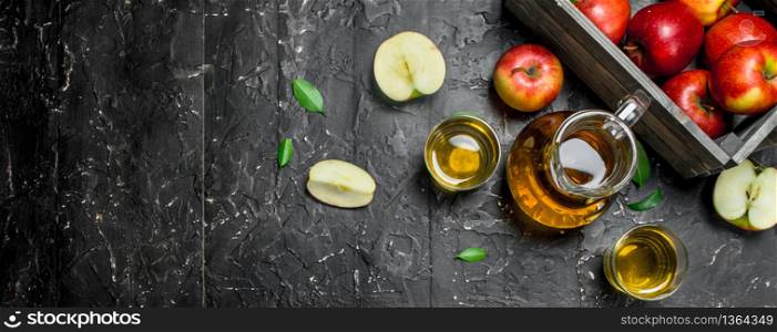 Apple juice in a glass jar with fresh apples in a box. On a dark rustic background. Apple juice in a glass jar with fresh apples in a box.