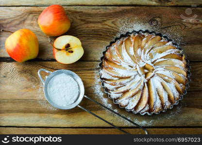 Apple pie, dessert tart with fresh fruits and caster sugar on wooden table, top view. Apple pie with fresh fruits