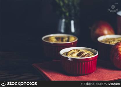Apple pie in ceramic baking molds ramekin on dark wooden table. Close up, shallow depth of the field. Romantic breakfast or supper with coffee.