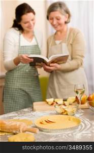 Apple pie recipe two women looking in cookbook happy baking