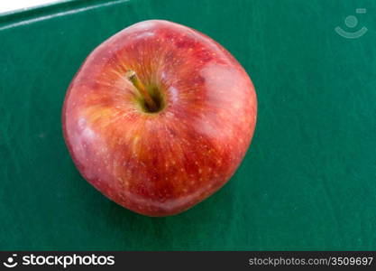 Apple red on a green book seen from above