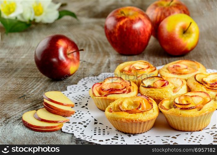 Apple shaped roses muffins on wooden background. Apple shaped roses muffins on wooden background. Sweet apple dessert pie. Homemade apple rose pastry.