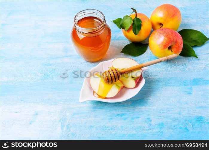Apple slices with honey on blue wooden background. Rosh hashanah concept. Jewesh new year symbols. Copy space.. Apple slices with honey on blue wooden background