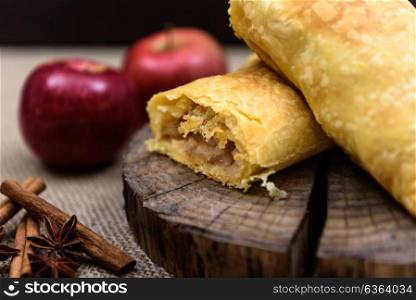 Apple strudel on wooden end of a tree with apples, cinnamon and star anise
