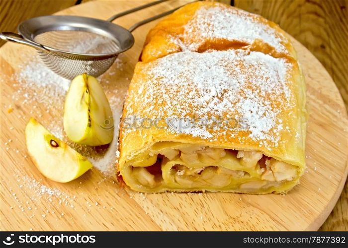 Apple strudel with icing sugar, strainer on a wooden boards background