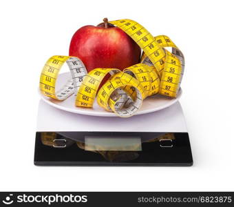 Apple with measuring tape on a digital kitchen scale