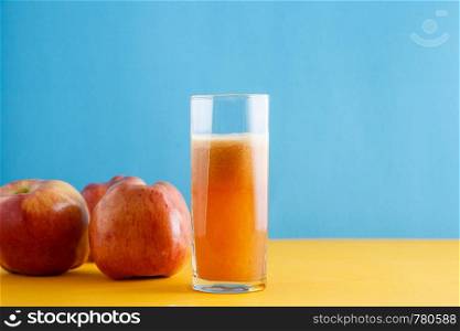 apples and a glass of natural Apple juice on a yellow-blue background