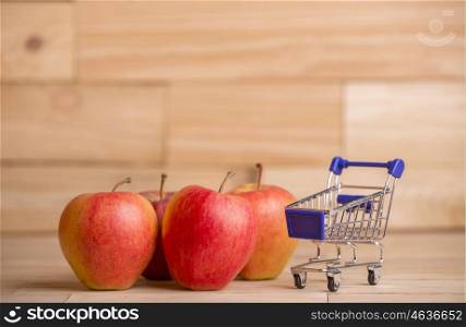 apples and a shopping cart on a wooden table, studio picture