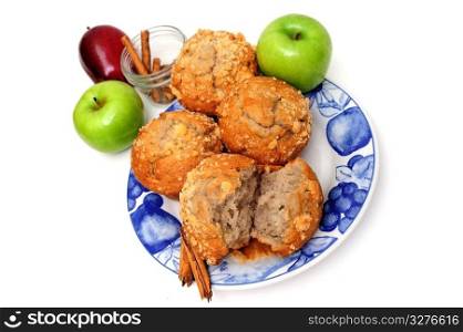 Apples and Muffins. Apple spice breakfast muffins on a county style blue and white plate with apples and cinnamon spice isolated on a white background