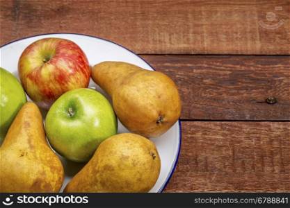 apples and pears on rustic red painted barn wood table with a copy space
