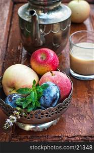 apples and plums in iron vase, teapot and cup of coffee