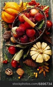 Apples in basket and autumn decorations on old wooden background