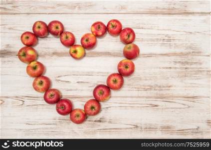 Apples in heart shape on rustic wooden background. Love concept