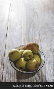 Apples in vintage metal cup on white wooden table
