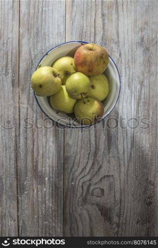 Apples in vintage metal cup on white wooden table