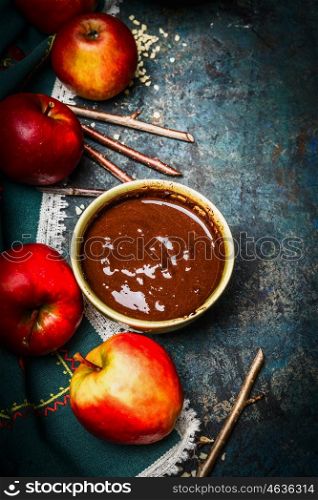 Apples, sticks and hot liquid chocolate on rustic background