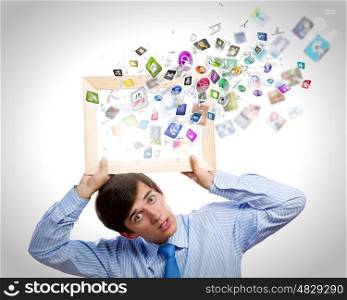 Application icons. Young businessman holding frame with icon flying out