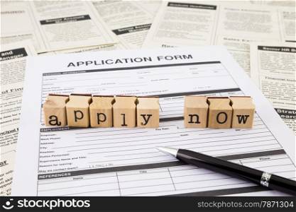 apply now word on wood stamps stacking on application form and fake classifieds ads
