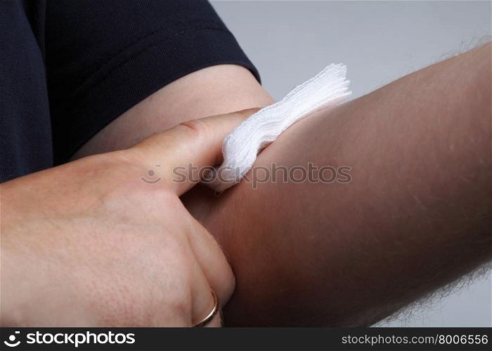 applying a cotton swab to an arm after blood sample