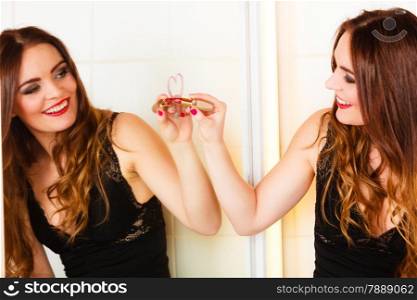 Applying makeup funny idea. Young pretty woman drawing heart sign symbol on mirror in bathroom.