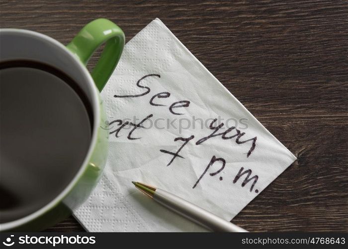 Appointing romantic date. Romantic message written on napkin and cup of coffee on wooden table