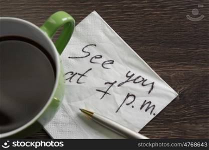 Appointing romantic date. Romantic message written on napkin and cup of coffee on wooden table