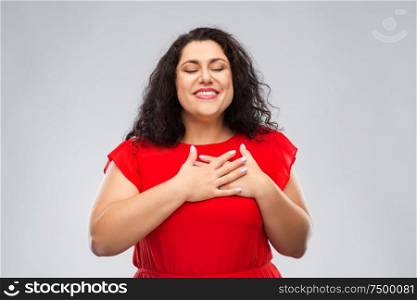 appreciation, love and sincere emotions concept - happy woman with closed eyes in red dress holding hands on chest or heart over grey background. happy woman holding hands on chest or heart