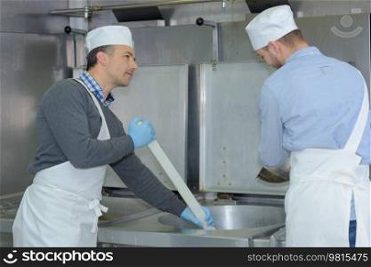 apprentice and chief preparing meat in restaurant kitchen