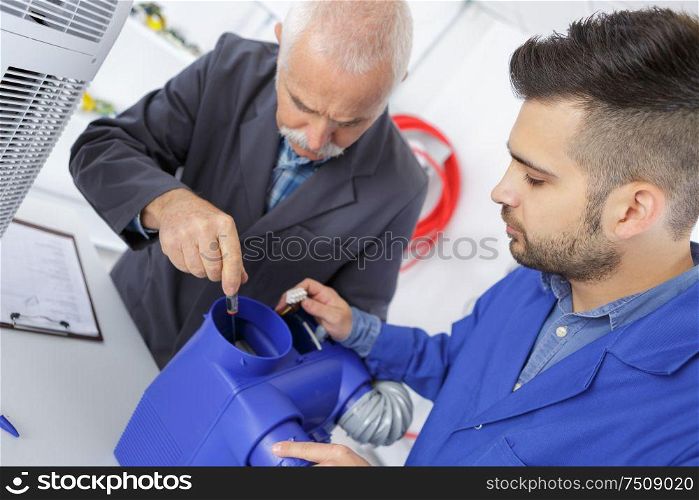 apprentice and teacher repairing an enginee