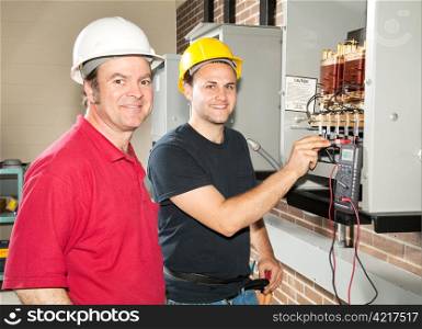 Apprentice electrician and his instructor reading the voltage on a power distribution center.