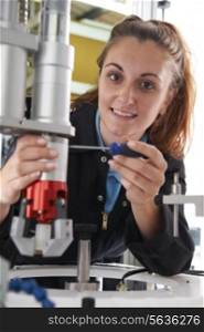 Apprentice Female Engineer Working On Machine In Factory