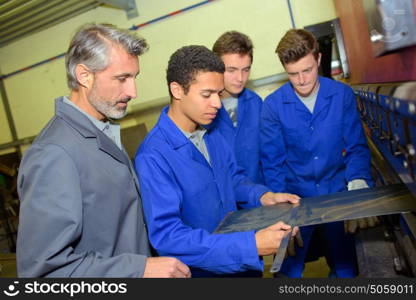 Apprentice measuring a piece of flat metal