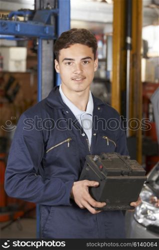 Apprentice Mechanic Holding Car Battery In Auto Repair Shop